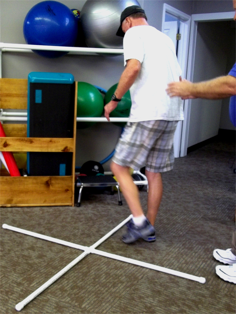 Patient Balancing and Stepping around 4 square equipment while Therapist behind and helping.