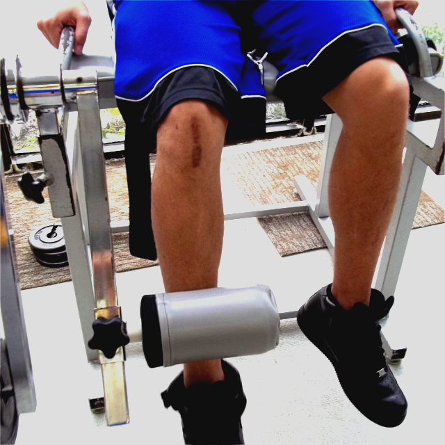 Man with Scar on Knee Using knee extension and ham string curl machine.